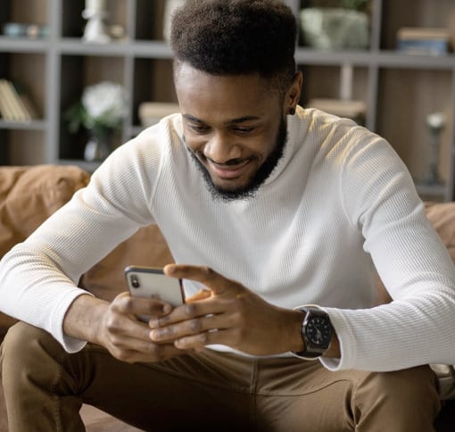 A young man happily texting on his phone.